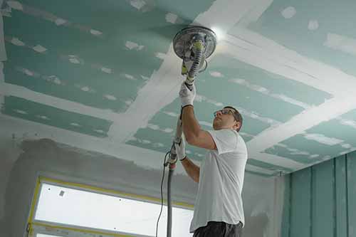 picture of contractor sanding ceiling before painting